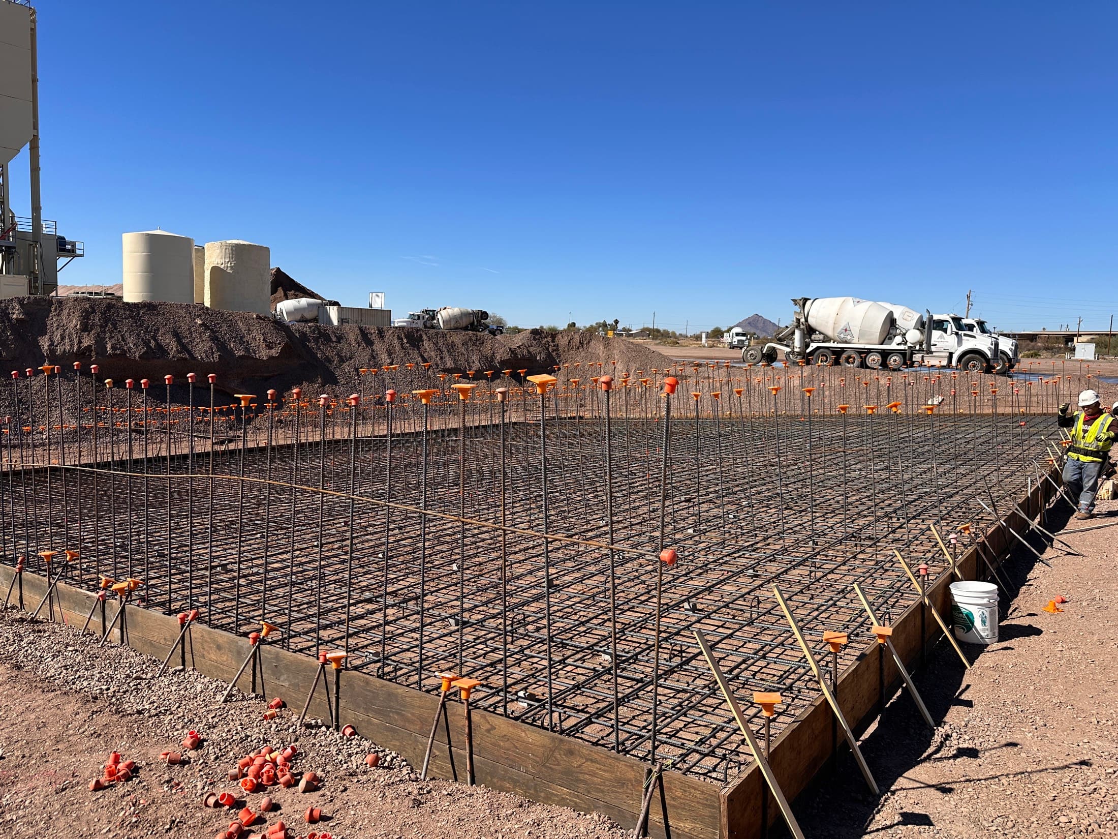 Heavy reinforcing mat tied for a plant foundation, batch plant behind