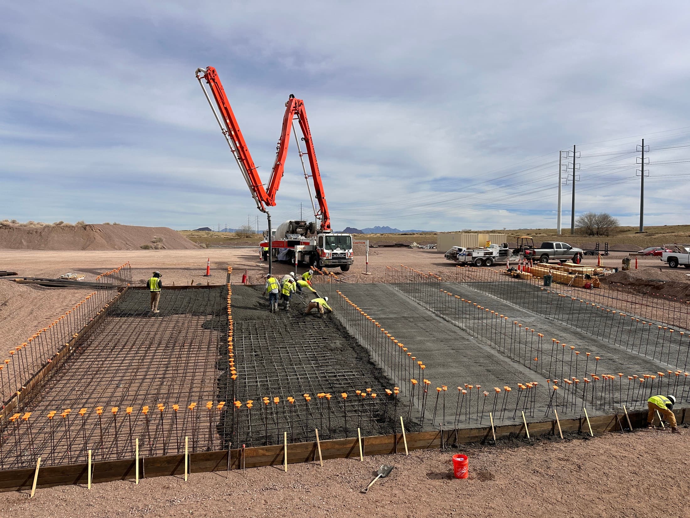 Two concrete pump booms working the same placement — a spare on site, not on call